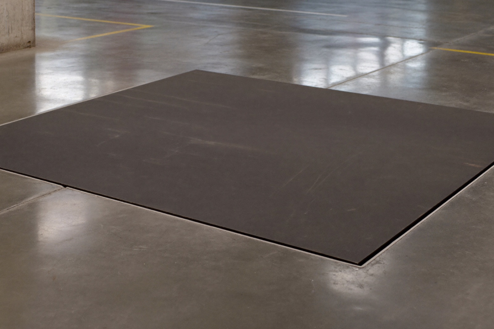 Steel lift deck sitting flush with a polished concrete industrial floor with edge marking