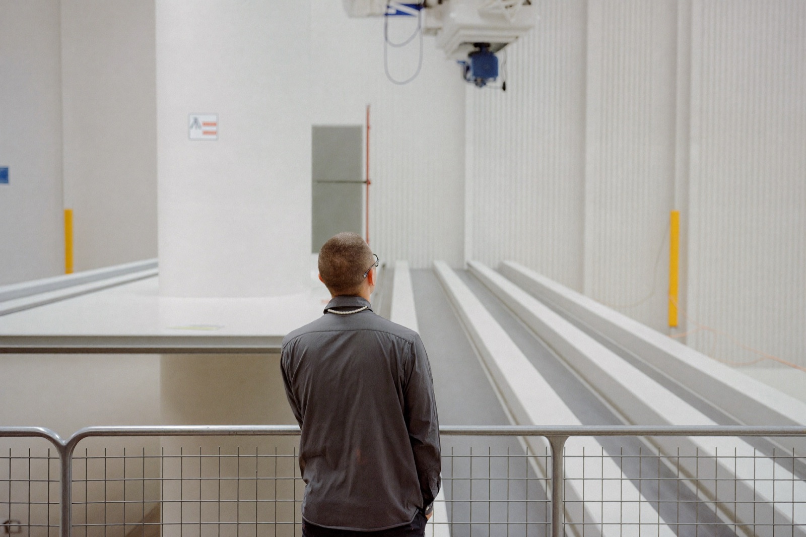 Technician at a guardrail working beside the column of a large gantry machining center