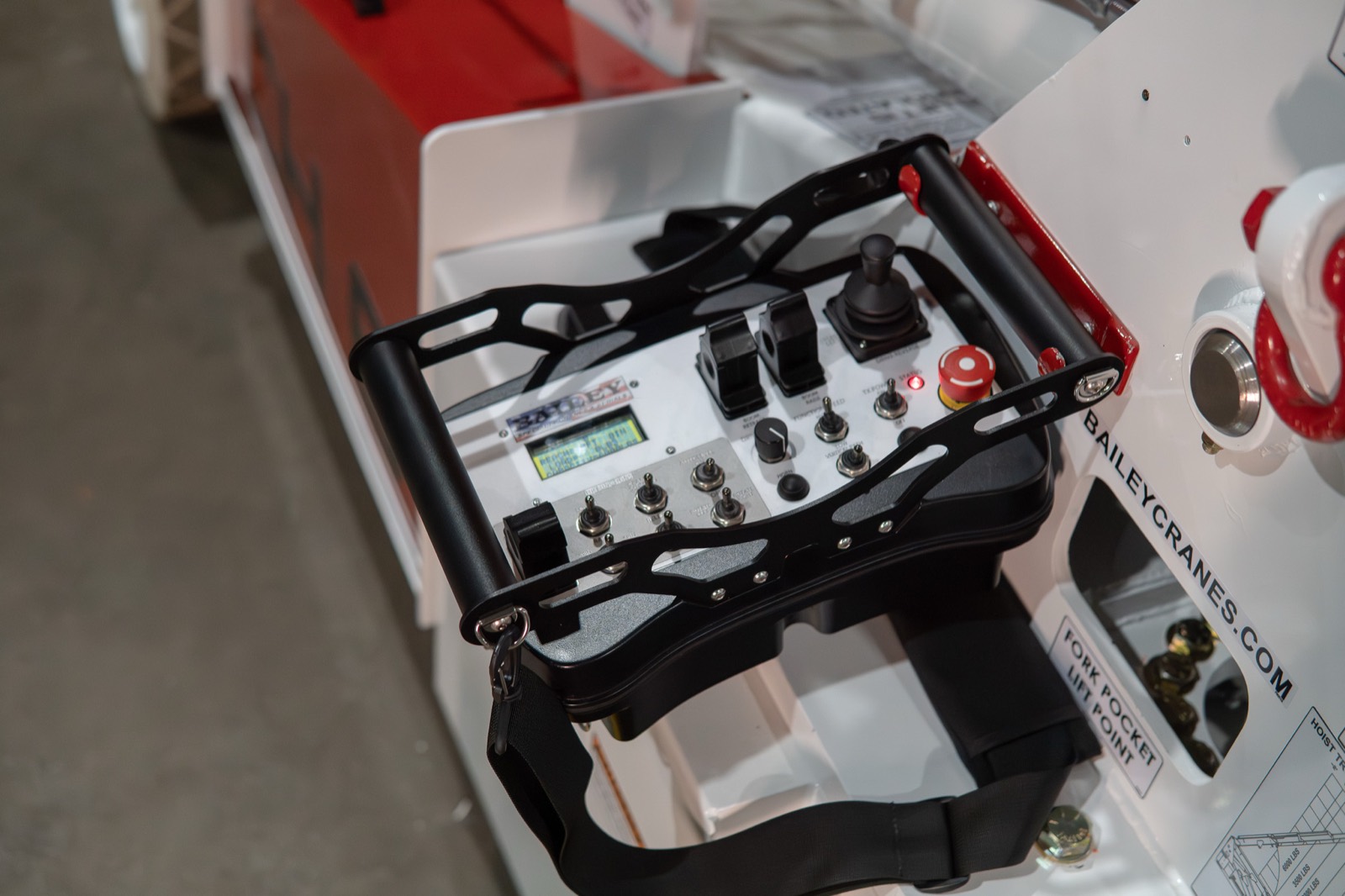 Handheld pendant controller for walk-behind operation of a Bailey pick-and-carry crane, with joystick, travel-speed switches, and emergency stop
